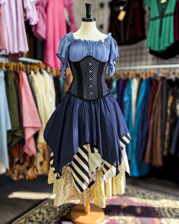 The Indigo Blue Linen Pixie Skirt by Faire Treasures displayed in a striped pirate styled outfit focusing on blues, blacks, and ivories.
