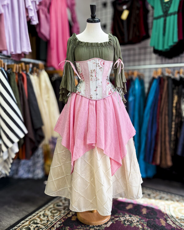 The Pale Pink Linen Pixie Skirt by Faire Treasures displayed in an outfit with pinks, greens, and ivory tones.