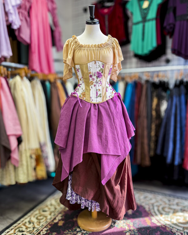 The Wisteria Linen Pixie Skirt by Faire Treasures displayed in an outfit with purples, tans, and browns.